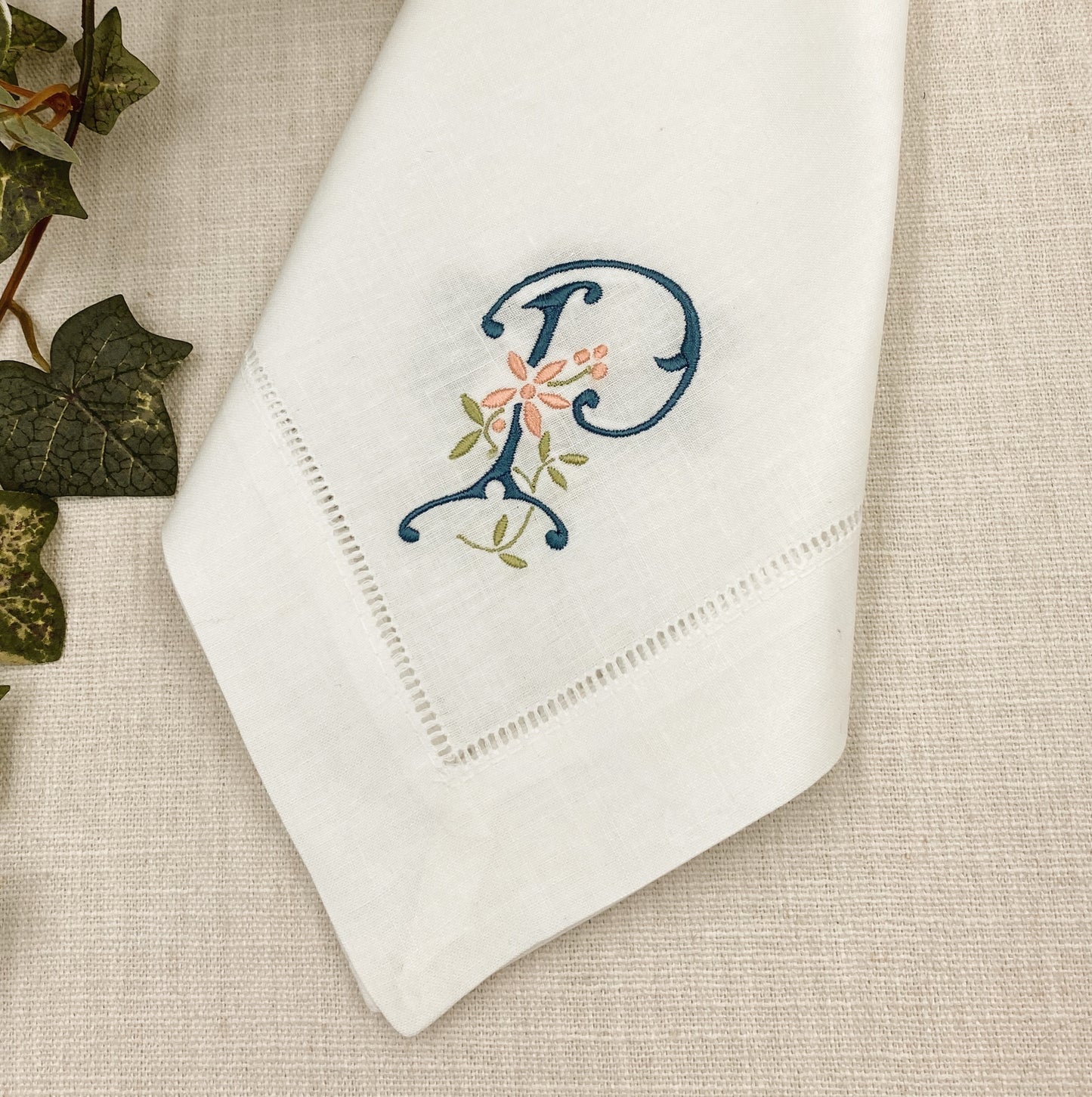 White hemstitch napkin with monogram angled on corner with the letter "P" in Copenhagen blue thread 